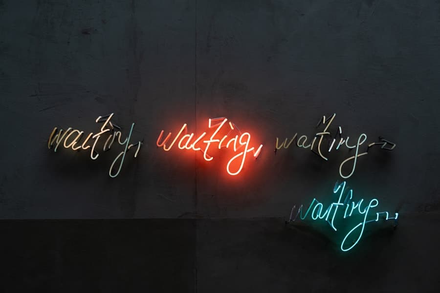 Neon wall art spelling the word "waiting" four times in white, red and teal cursive