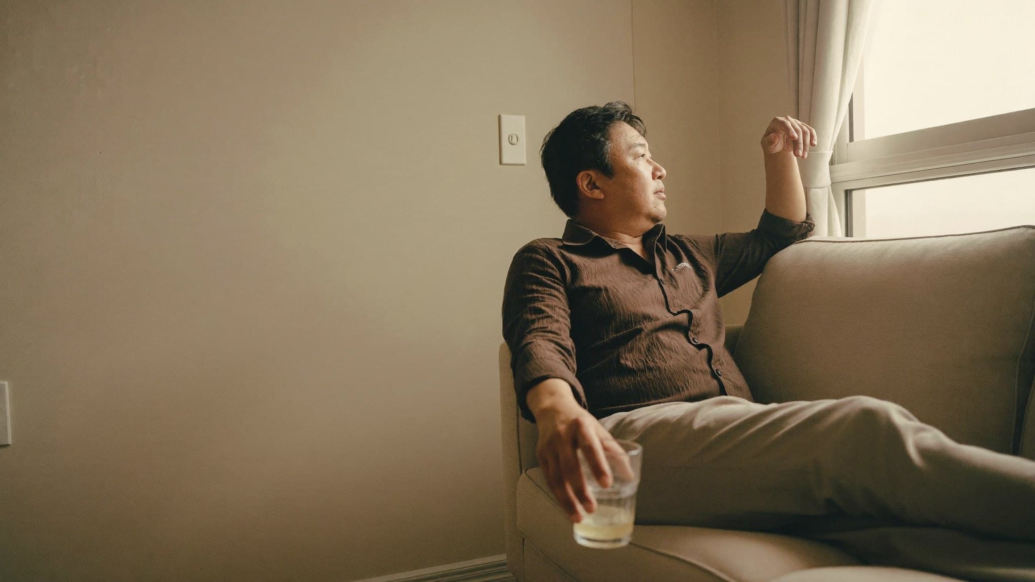 Seorang lelaki berumur lima puluhan berehat di sofa rumahnya pada waktu petang, memandang ke luar tingkap.