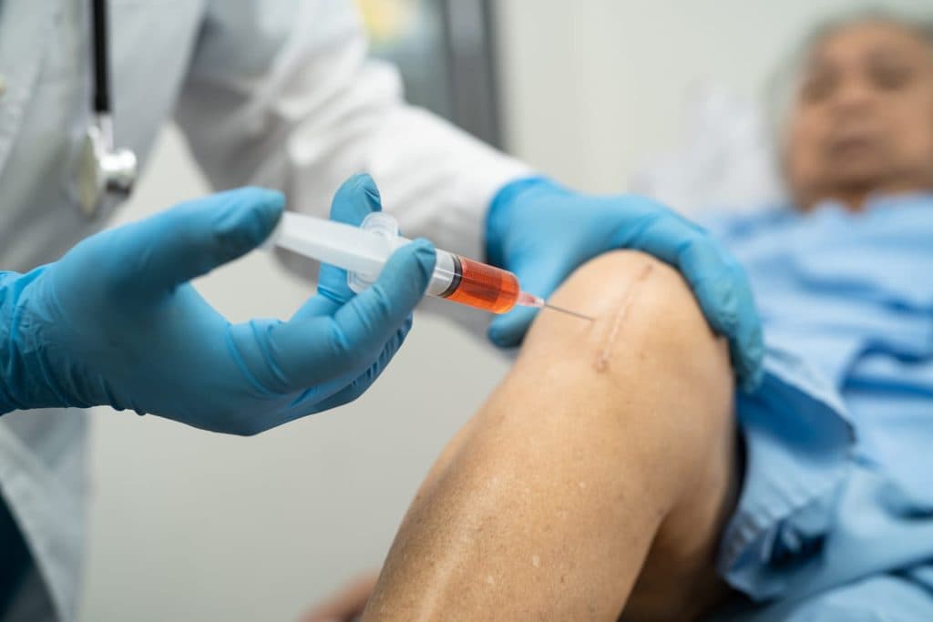 A doctor injecting platelet-rich plasma into an older woman's knee