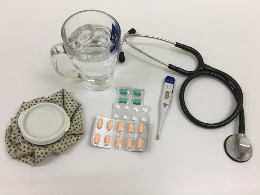 白色桌面上摆放着水杯、听诊器、电子体温计、两板药片和一个冷敷袋